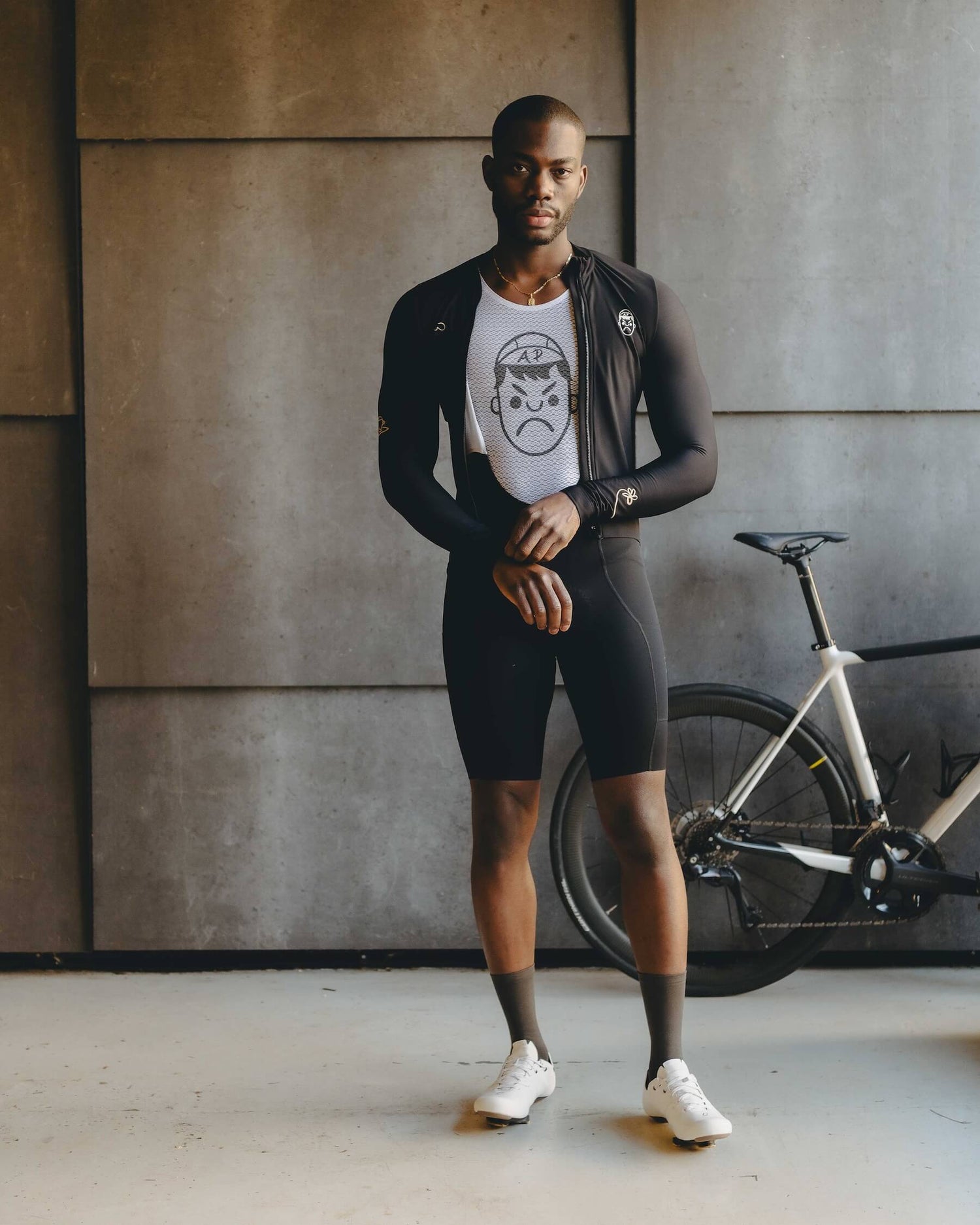 A cyclist standing wearing an Angry Pablo Mesh White Base Layer and long sleeve cycling jersey